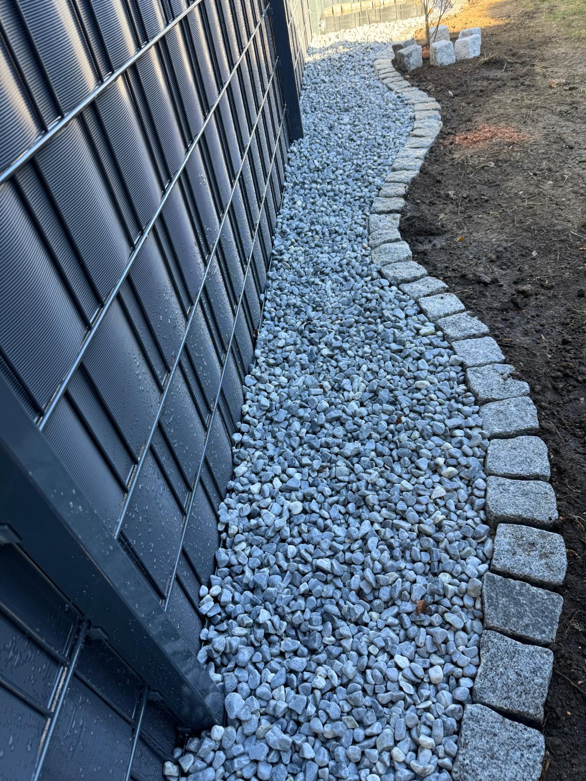 Ein gepflegter Steingarten mit grauem Kies und einer klar definierten Steinbegrenzung